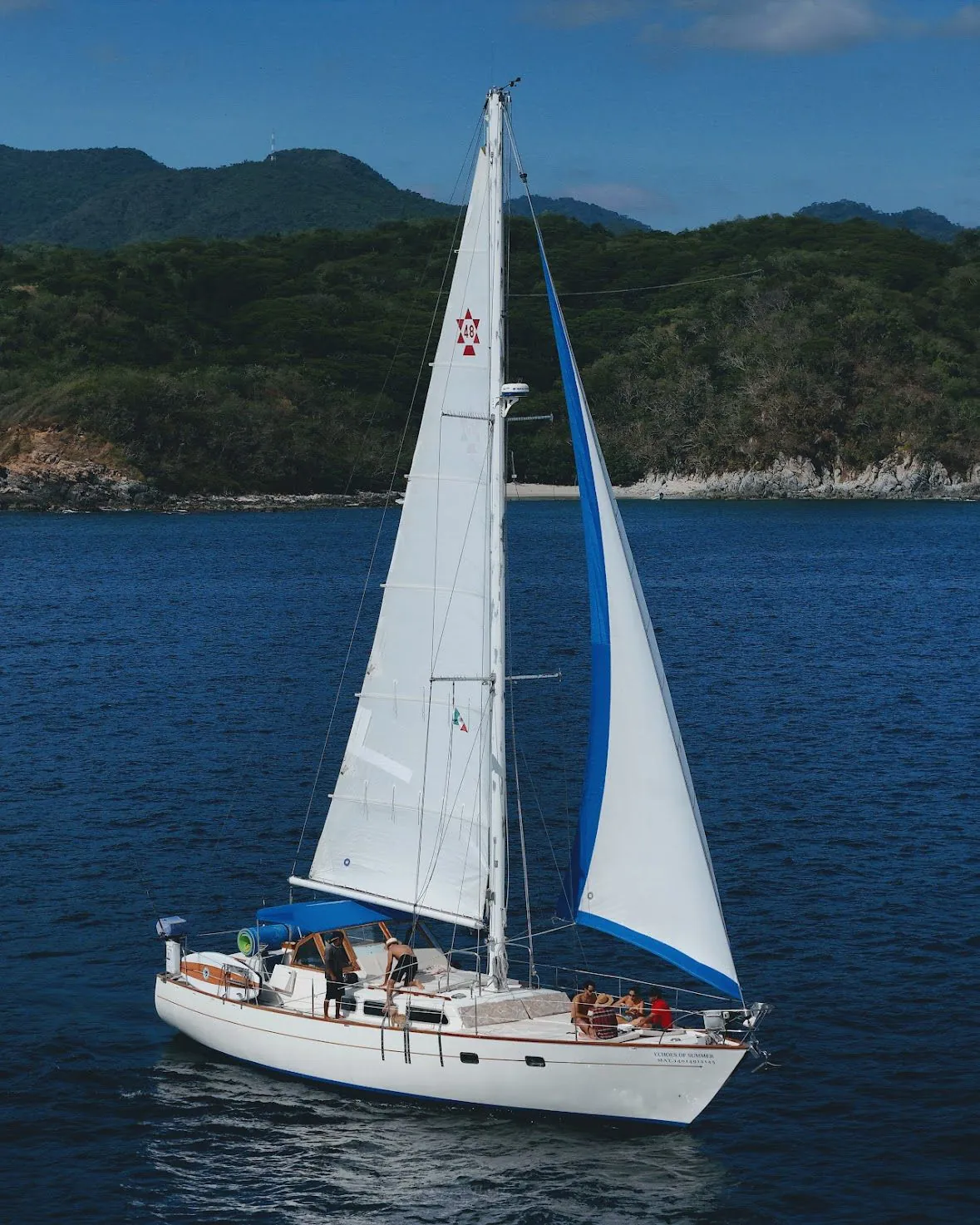 Retreat sailboat on the bay below the green hills of Puerto Vallarta